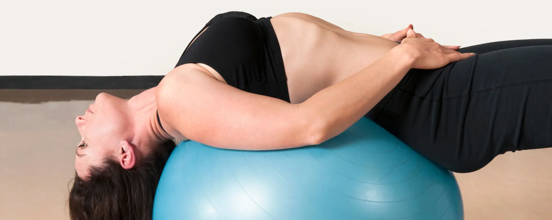 Woman lying on stability ball doing posture corrector exercises.
